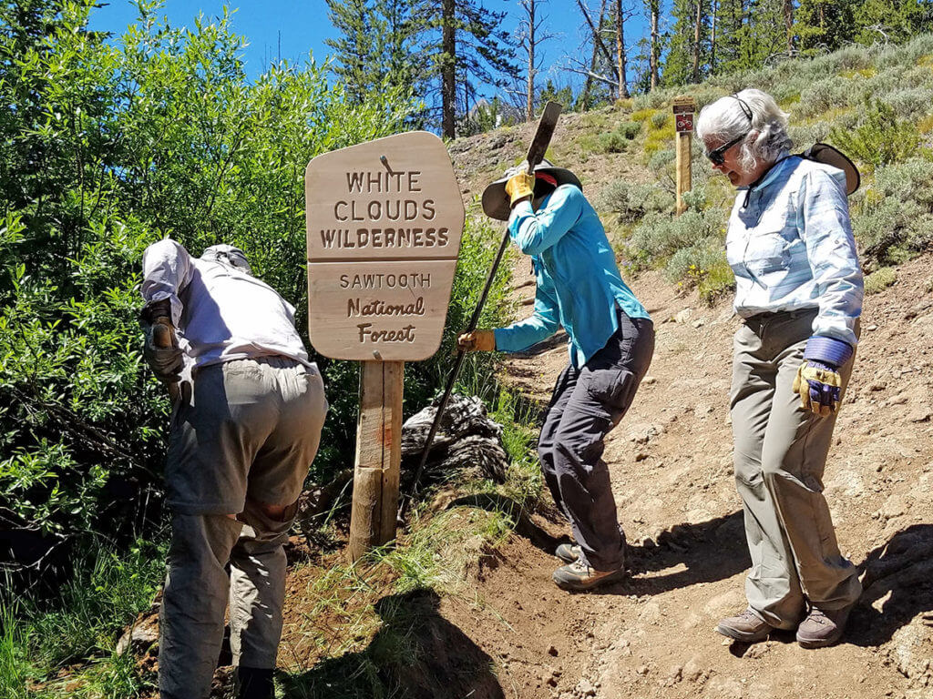 Women putting up 'White Clouds Wilderness' sign post