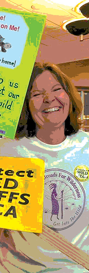 A woman in a Great Old Broads shirt smiling with signs